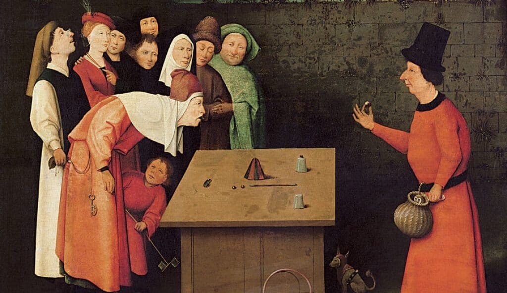 يقوم ساحر بأداء خدعة الكأس بينما يسرق رجل محفظة النقود لأحد المتفرجين، حوالي عام 1475، <em>المشعوذ</em> بواسطة هيرونيموس بوش.